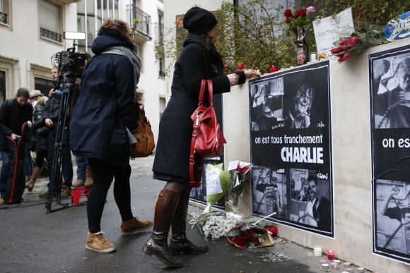 Une femme dépose des fleurs devant les bureaux de Charlie Hebdo le 7 janvier 2014