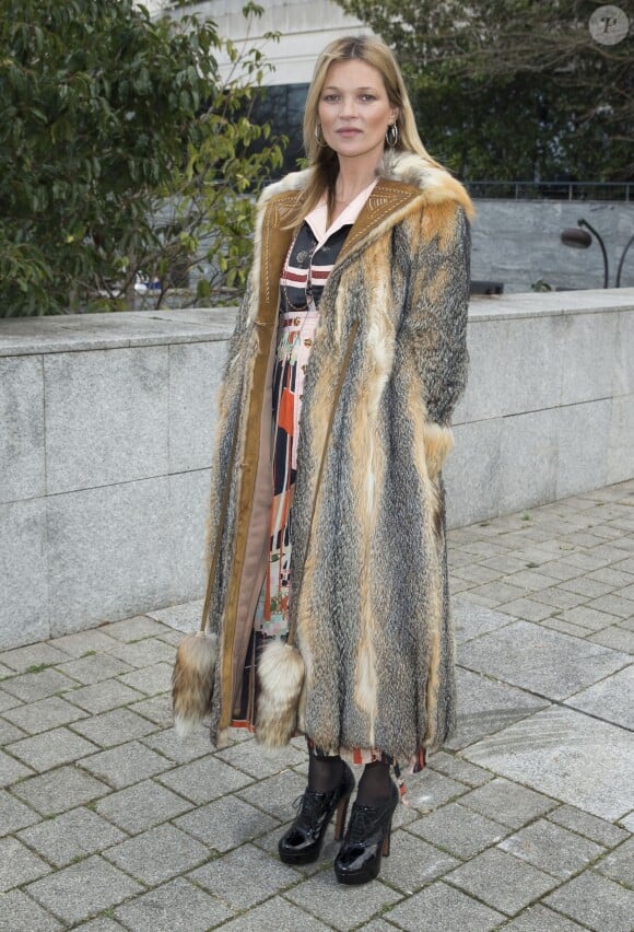 Kate Moss, habillée d'un manteau en fourrure, d'une robe Louis Vuitton et de souliers vernis noirs Alaïa, assiste au défilé de mode homme Louis Vuitton prêt-à-porter automne-hiver 2015-2016. Paris, le 22 janvier 2015.