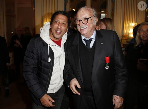 Jean Becker pose avec Smaïn lors de la cérémonie le décorant de Officier de l'ordre national de la Légion d’honneur au Ministère de la Culture à Paris, le 30 mars 2015
