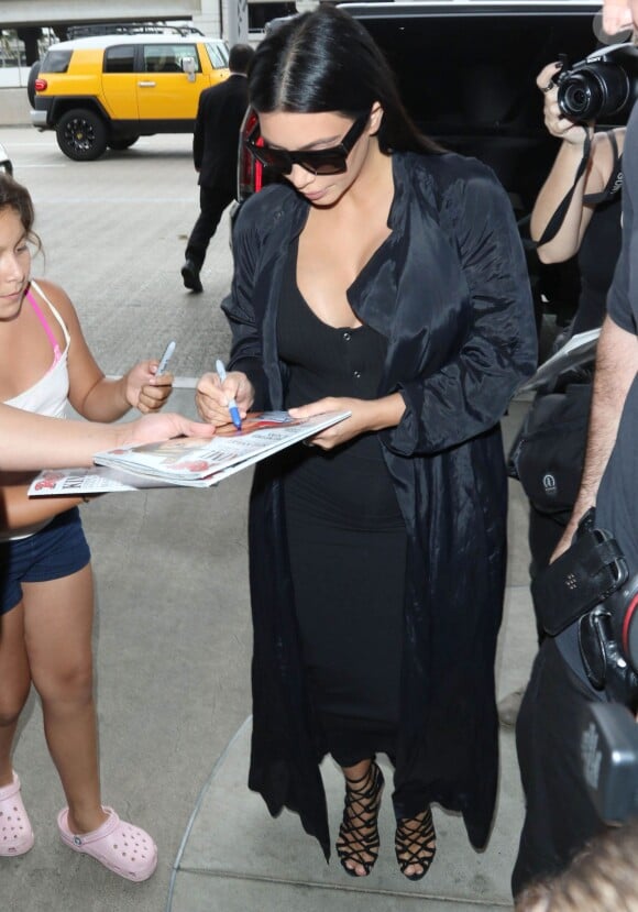 Kim Kardashian (enceinte) signe des autographes en arrivant à l'aéroport LAX de Los Angeles pour prendre un avion. Le 19 juillet 2015