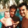 Alex Goude, Romain et leur bébé Elliot posent ensemble dans la piscine. Juin 2015.