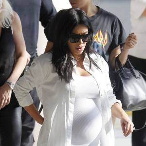 Exclusif - Mal de dos ? Kim Kardashian, enceinte et toute de blanc vêtue, arrive à l'aéroport de Louis Armstrong à la Nouvelle-Orléans. Le 4 août 2015.