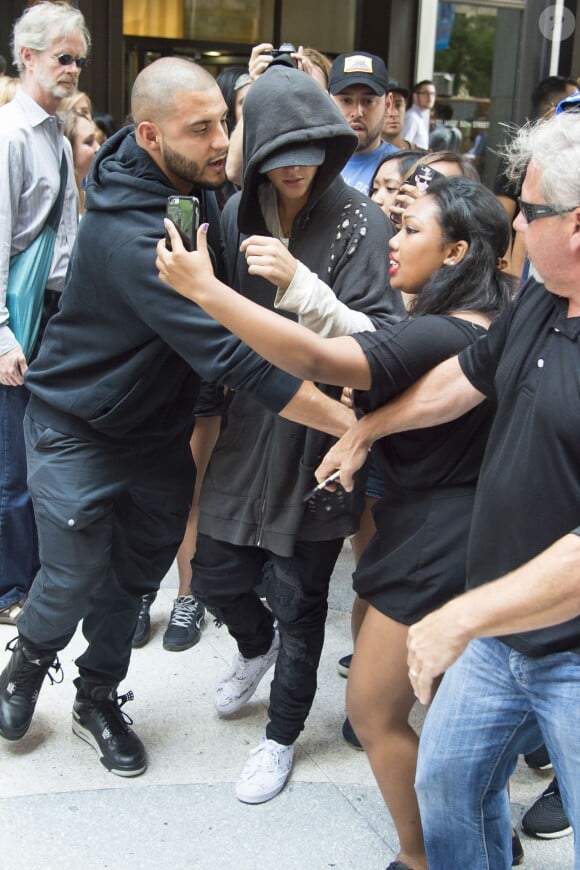 Justin Bieber, assailli par ses fans, se promène avec ses gardes du corps dans les rues de Manhattan à New York. Le 24 août 2015