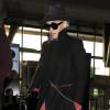 Rita Ora, toute de noir vêtue à l'aéroport d'Heathrow, porte un manteau Victoria Beckham (collection automne-hiver 2014) et des bottines Saint Laurent. Londres, le 17 mars 2016.