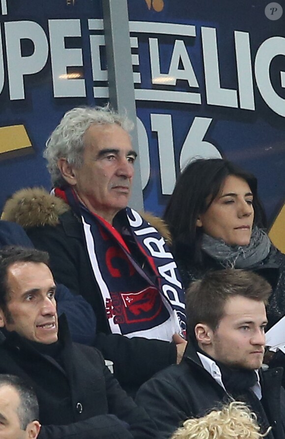 Raymond Domenech et sa compagne Estelle Denis, dans les tribunes de la rencontre finale de la Coupe de la Ligue PSG-Lille au Stade de France à Paris, le 23 avril 2016.
