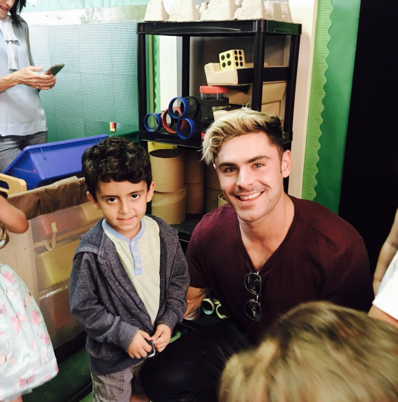 Zac Efron dévoile sa nouvelle coupe de cheveux, similaire à celle de Justin Bieber lors des American Music Awards 2015, alors qu'il rend visite à des enfants dans une école primaire. Photo publiée sur Twitter, le 2 juin 2016