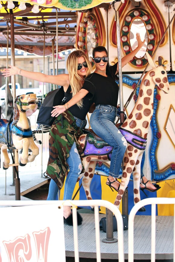 Les soeurs Kardashian retombent en enfance ! Kourtney et Khloé font un tour de carrousel à Encino. Le 23 août 2016.