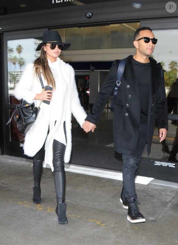 Exclusif - John Legend et sa femme Chrissy Teigen, habillée d'un manteau Sanctuary, d'une chemise blanche, d'un pantalon en cuir J BRAND et de chaussures noires, quittent l'aéroport LAX de Los Angeles. Le 7 janvier 2017.