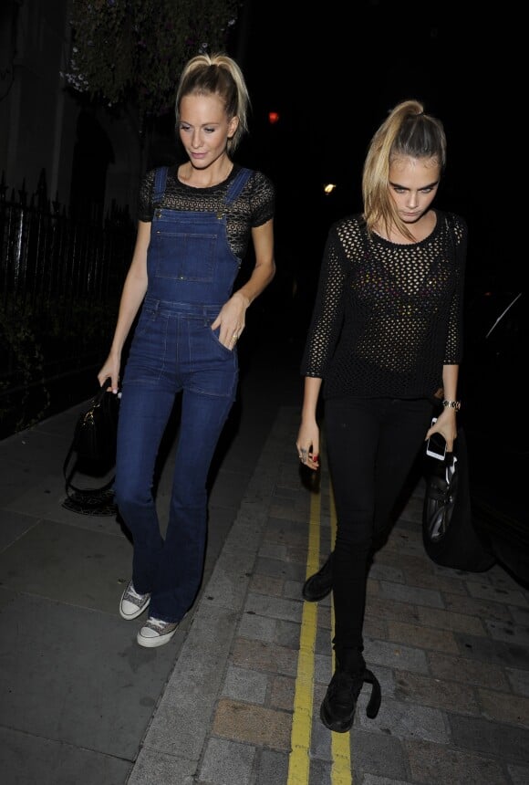 Cara (chaussures Chanel) et Poppy Delevingne (salopette Frame Denim, chaussures Converse) vont dîner à Londres le 3 octobre 2014.