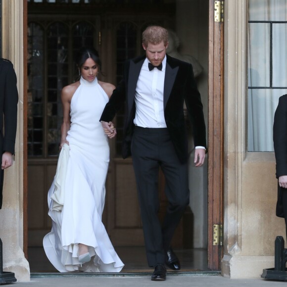 Le prince Harry et Meghan Markle, duchesse de Sussex quittant le château de Windsor à bord d'une Jaguar Type E cabriolet en tenue de soirée, après leur cérémonie de mariage et la réception à St George's Hall, pour se rendre à la réception à Frogmore House, le 19 mai 2018.