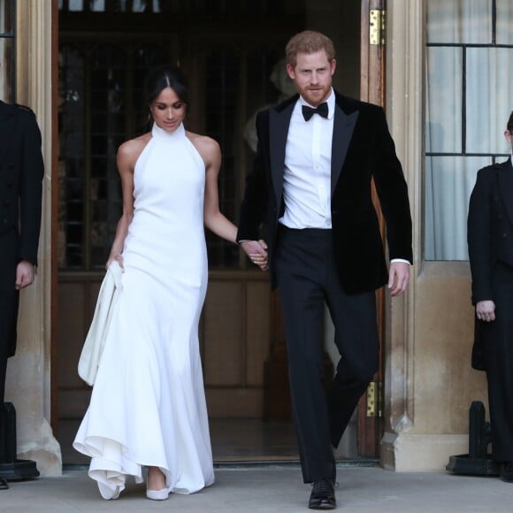 Le prince Harry, duc de Sussex, et Meghan Markle, duchesse de Sussex quittent le château de Windsor à bord d'une Jaguar Type E cabriolet en tenue de soirée après leur cérémonie de mariage, pour se rendre à la réception à "Frogmore House" à Windsor le 19 mai 2018.  The newly married Duke and Duchess of Sussex, Meghan Markle and Prince Harry, leaving Windsor Castle after their wedding to attend an evening reception at Frogmore House, hosted by the Prince of Wales. May 19th, 2018.19/05/2018 - Windsor