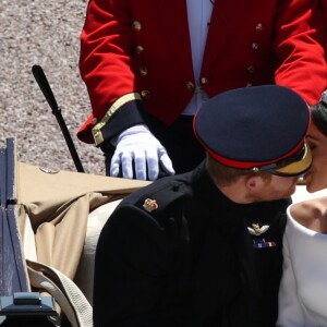 Le prince Harry et Meghan Markle s'embrassent lors de leur procession à travers Windsor le 19 mai 2018 après leur mariage en la chapelle St George.