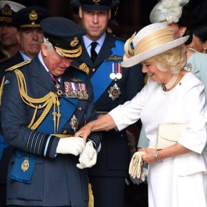 Le prince Charles se fait aider par son épouse Camilla Parker Bowles avec ses gants à l'abbaye de Westminster, le 10 juillet 2018 à Londres, lors du service marquant le centenaire de la Royal Air Force (RAF).