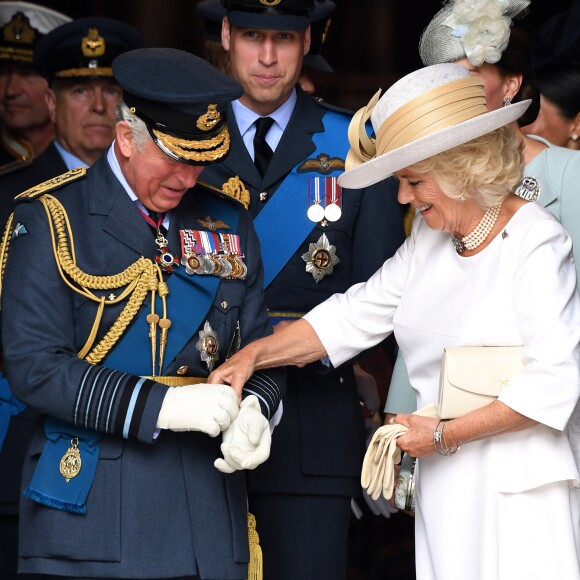 Le prince Charles se fait aider par son épouse Camilla Parker Bowles avec ses gants à l'abbaye de Westminster, le 10 juillet 2018 à Londres, lors du service marquant le centenaire de la Royal Air Force (RAF).