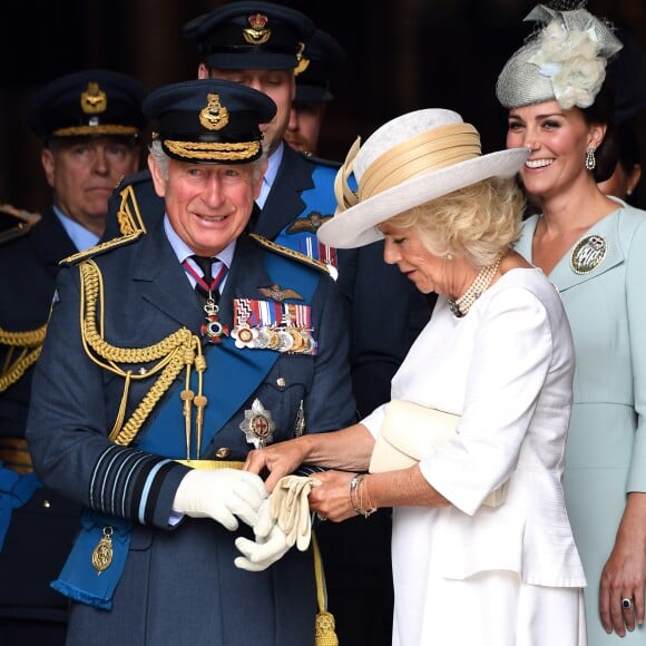 Le prince Charles se fait aider par son épouse Camilla Parker Bowles avec ses gants à l'abbaye de Westminster, le 10 juillet 2018 à Londres, lors du service marquant le centenaire de la Royal Air Force (RAF).