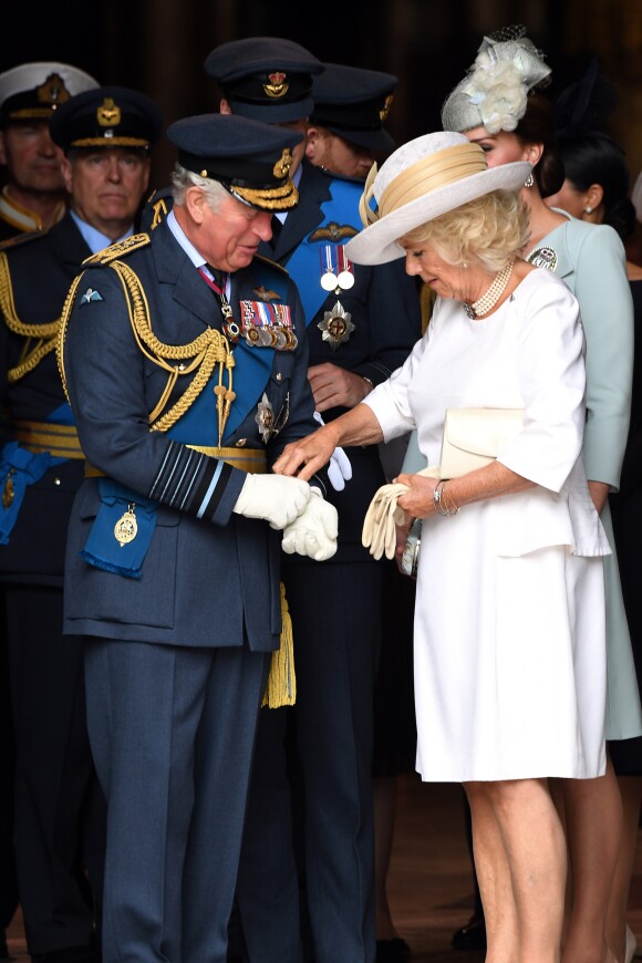 Le prince Charles se fait aider par son épouse Camilla Parker Bowles avec ses gants à l'abbaye de Westminster, le 10 juillet 2018 à Londres, lors du service marquant le centenaire de la Royal Air Force (RAF).