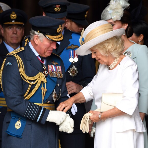Le prince Charles se fait aider par son épouse Camilla Parker Bowles avec ses gants à l'abbaye de Westminster, le 10 juillet 2018 à Londres, lors du service marquant le centenaire de la Royal Air Force (RAF).