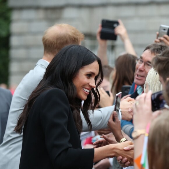 Le prince Harry, duc de Sussex et sa femme Meghan Markle, duchesse de Sussex saluent la foule lors de leur visite au collège de la trinité à Dublin le 11 juillet 2018