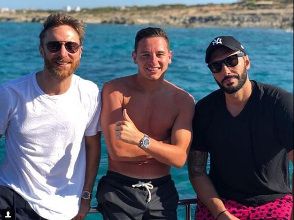 Florian Thauvin, tout rouge, pose avec David Guetta à Ibiza le 25 juillet 2018.