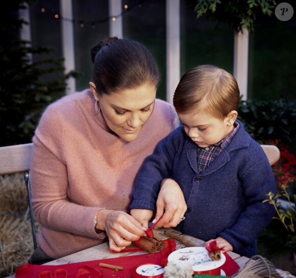La princesse héritière Victoria de Suède et le prince Oscar en plein atelier déco de Noël, nouant un fagot de bâtons de cannelle, photo officielle pour les fêtes de fin d'année 2018. ©Tiina Björkbacka / Cour royale de Suède