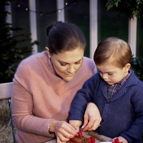 La princesse héritière Victoria de Suède et le prince Oscar en plein atelier déco de Noël, nouant un fagot de bâtons de cannelle, photo officielle pour les fêtes de fin d'année 2018. ©Tiina Björkbacka / Cour royale de Suède