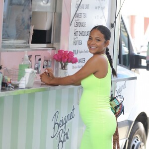 Christina Milian enceinte porte une robe vert fluo très moulante devant son Beignet Box truck à Studio City, Los Angeles, le 29 août 2019