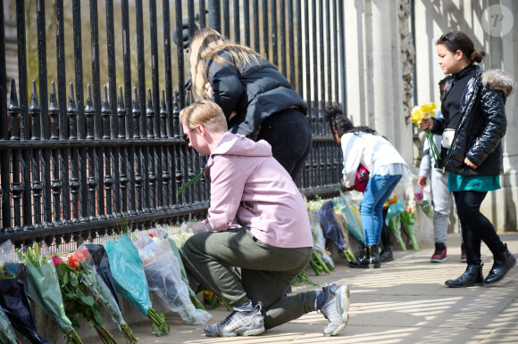 Les Britanniques déposent des fleurs devant les grilles de Buckingham Palace après l'annonce du décès du prince Philip à Londres, le 9 avril 2021.