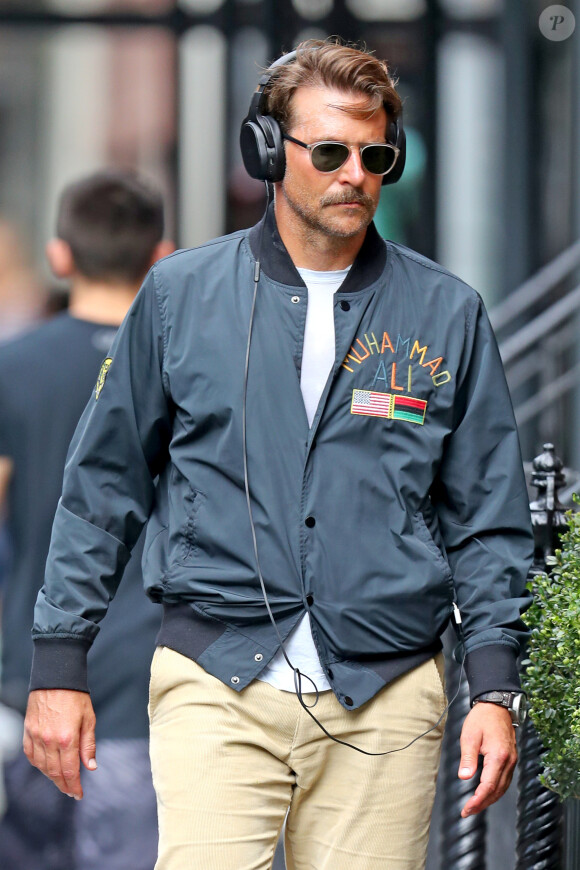 Exclusif - Bradley Cooper se promène à New York. L'acteur âgé de 44 ans était bronzé, portait une longue moustache, un large casque, une veste en nylon Muhammad Ali, un pantalon beige et des baskets grises, le 4 septembre 2019.