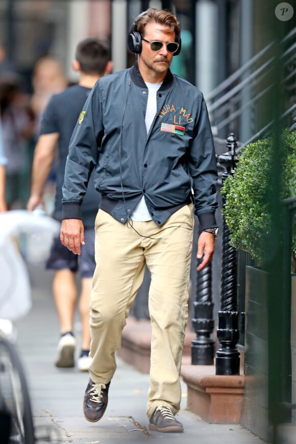 Exclusif - Bradley Cooper se promène à New York. L'acteur âgé de 44 ans était bronzé, portait une longue moustache, un large casque, une veste en nylon Muhammad Ali, un pantalon beige et des baskets grises, le 4 septembre 2019.