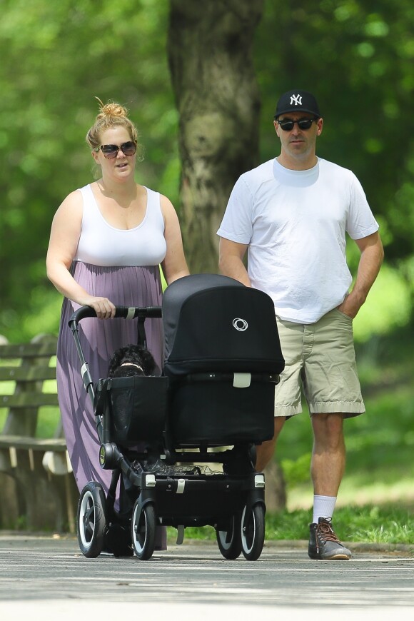 Amy Schumer et son mari Chris Fischer promènent leur fils Gene Attell Fischer en poussette dans un parc à New York, le 18 mai 2019.