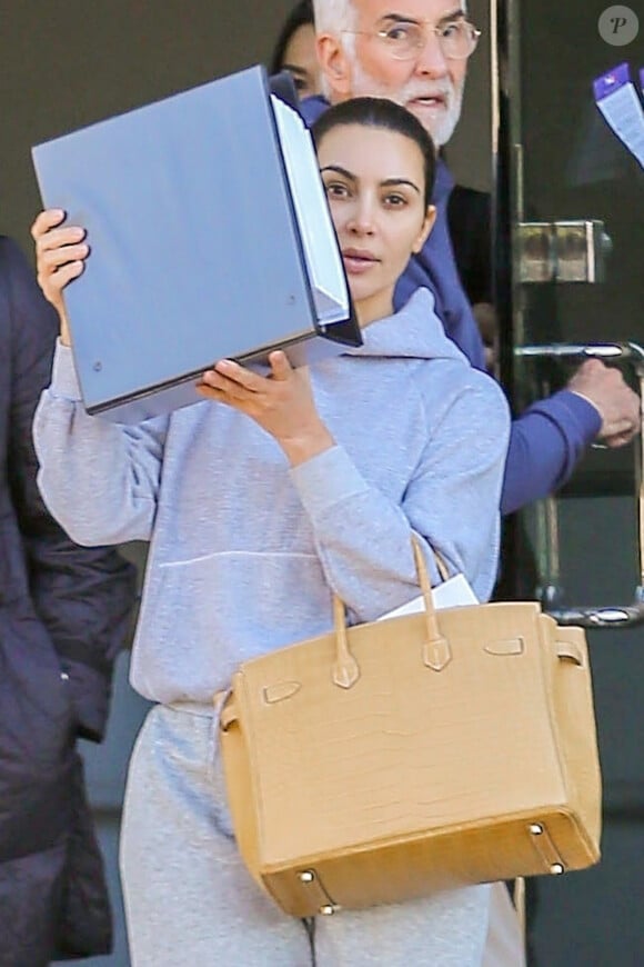 Kim Kardashian (sans maquillage) essaie de se cacher des photographes avec un classeur à la sortie des bureaux de son mari K. West à Los Angeles, le 6 janvier 2020.
