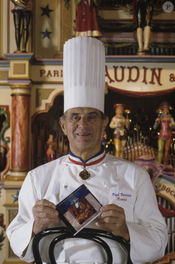 En France, Paul Bocuse posant au château d'Ecully, dans lequel est installée l'école des Arts Culinaires et de l'hôtellerie. Il pose devant un limonaire ( ou orgue de barbarie ) Gaudin datant de 1895, provenant de sa collection le 17 novembre 1993.17/11/1993 -