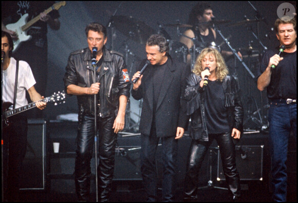 Johnny Hallyday, Michel Sardou, Véronique Sanson et Eddy Michell sur scène pour un concert lors de la tournée des Enfoirés en 1989.