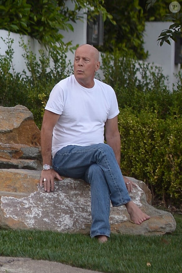 Exclusif - Bruce Willis est assis pieds nus sur un rocher et regarde passer les voitures sur Sunset Boulevard à Los Angeles, le 22 septembre 2019.