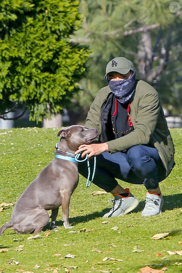 Exclusif - Henry Golding, équipé d'un foulard en guise de masque, promène son pitbull Stella dans un parc, en marge du confinement à Santa Monica, le 23 avril 2020.