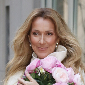 Celine Dion rayonnante et très souriante dans un ensemble pull écru et jupe bouffante fleurie salue ses fans à la sortie de son hôtel à New York, le 8 mars 2020