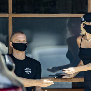 Exclusif - Miley Cyrus et son compagnon Cody Simpson, protégés d'un masque contre le coronavirus (Covid-19), vont chercher un café à emporter à Calabasas, dans l'établissement fréquenté par M. Fox et MGK. Le 16 juin 2020.  Exclusive - Miley Cyrus and Cody Simpson appear to still be going strong despite Miley's track record of getting bored and moving on to new things. The duo was seen picking up coffee from the same coffee shop where M. Fox and MGK started their PDA amidst Megan's breakup with B. Austin Green. Miley looked fresh in a black string spaghetti strap tank top and fitting black shorts. She also wore a matching 'Daddy' hat and black COVID mask. Calabasas. June 16, 2020. 