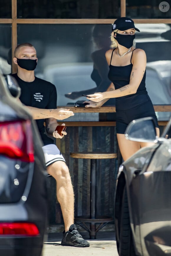 Exclusif - Miley Cyrus et son compagnon Cody Simpson, protégés d'un masque contre le coronavirus (Covid-19), vont chercher un café à emporter à Calabasas, dans l'établissement fréquenté par M. Fox et MGK. Le 16 juin 2020.  Exclusive - Miley Cyrus and Cody Simpson appear to still be going strong despite Miley's track record of getting bored and moving on to new things. The duo was seen picking up coffee from the same coffee shop where M. Fox and MGK started their PDA amidst Megan's breakup with B. Austin Green. Miley looked fresh in a black string spaghetti strap tank top and fitting black shorts. She also wore a matching 'Daddy' hat and black COVID mask. Calabasas. June 16, 2020. 