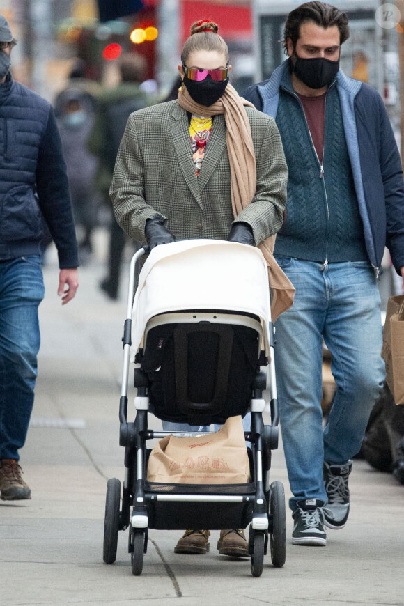 Gigi Hadid fait du shopping avec sa fille Khai Hadid Malik dans le West Village de New York le 15 janvier 2021. Le mannequin de 25 ans poussait une poussette Bugaboo Lynx et portait une écharpe, un blazer à carreaux avec de larges épaulettes, un jean déchiré et des bottes en cuir marron.