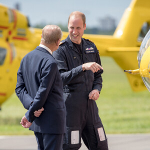 La reine Elisabeth II d'Angleterre et le prince Philip, duc d'Edimbourg visitent avec leur petit-fils prince William, duc de Cambridge, la nouvelle base East Anglian Air Ambulance à l'aéroport de Cambridge où il travaille à Cambridge, le 13 juillet 2016.