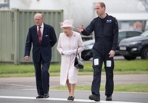 La reine Elisabeth II d'Angleterre et le prince Philip, duc d'Edimbourg visitent avec leur petit-fils prince William, duc de Cambridge, la nouvelle base East Anglian Air Ambulance à l'aéroport de Cambridge où il travaille à Cambridge, le 13 juillet 2016. 