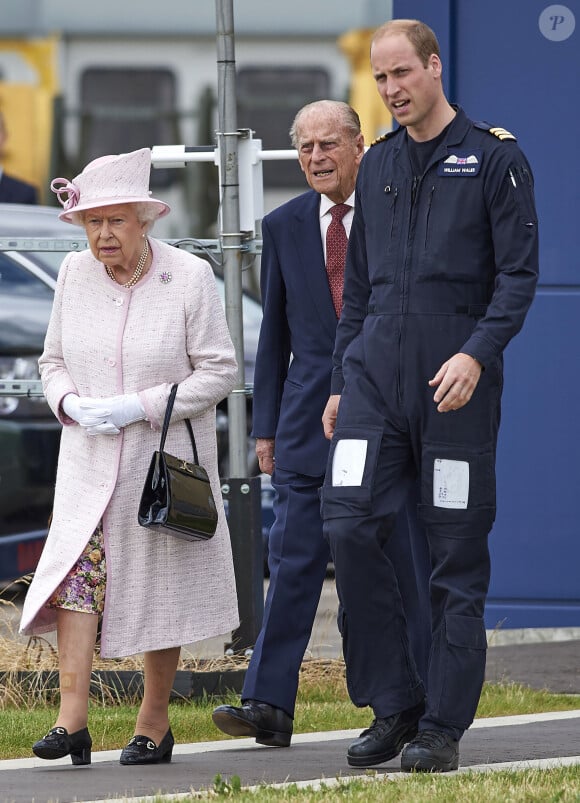 La reine Elisabeth II d'Angleterre et le prince Philip, duc d'Edimbourg visitent avec leur petit-fils prince William, duc de Cambridge, la nouvelle base East Anglian Air Ambulance à l'aéroport de Cambridge où il travaille à Cambridge, le 13 juillet 2016.