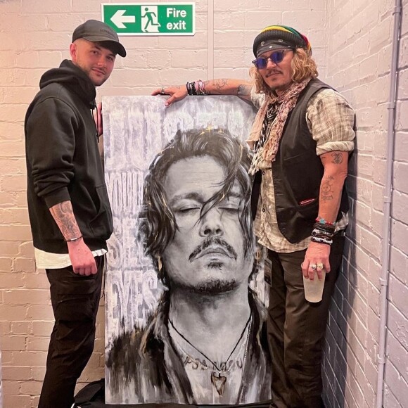L'artiste Scott Greenwood présente son oeuvre à Johnny Depp à l'o2 apollo de Manchester, Royaume Uni, le 4 juin 2022. Johnny Depp a signé des autographe de copies pour toute la famille de l'artiste.