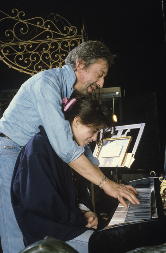 En France, à Paris, Serge Gainsbourg chez lui avec sa fille Charlotte dans son hotel particulier de la rue de Verneuil, posant au milieu de son bric-à-brac où il entasse des objets hétéroclites en mai 1985. © Michel Marizy via Bestimage