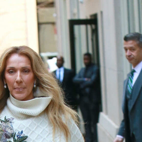Celine Dion rayonnante et très souriante dans un ensemble pull écru et jupe bouffante fleurie salue ses fans à la sortie de son hôtel à New York, le 8 mars 2020 
