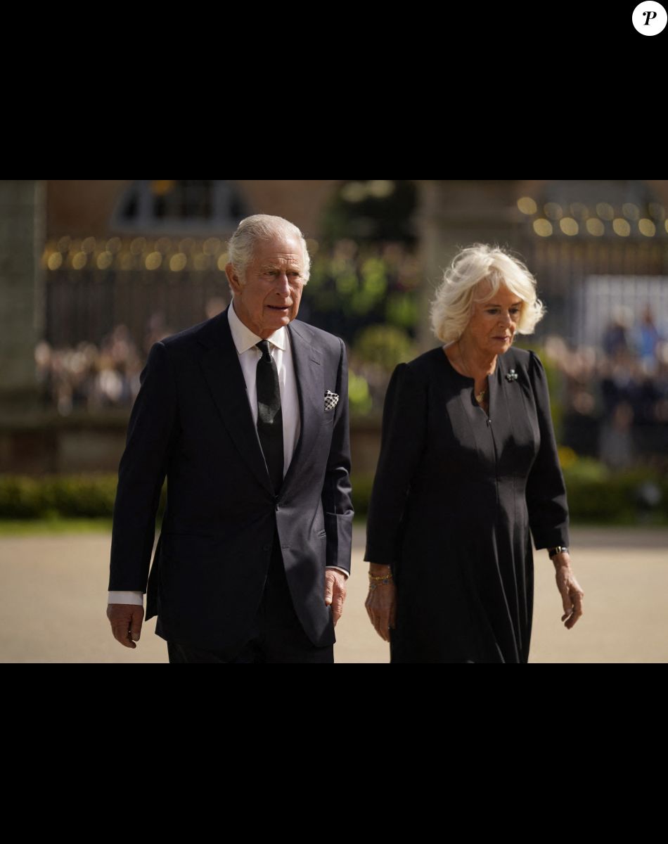 Le roi Charles III d'Angleterre et la reine consort Camilla Parker Bowles marchent le long des fleurs déposées en hommage à la reine Elisaberh II d'Angleterre, décédée le 8 septembre, devant le château de Hillsborough. Le 13 septembre 2022