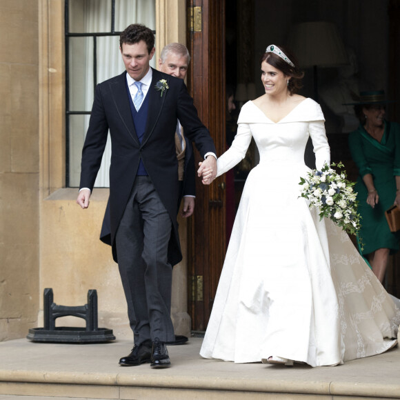 La princesse Eugénie et son mari Jack Brooksbank quittent le château de Windsor après leur mariage à bord d'une Aston Martin le 12 octobre 2018 sous le regard du père de la princesse Eugénie, le Duc d'York, le prince Andrew. 