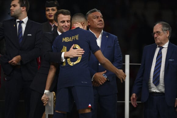 Kylian Mbappé accolade avec Emmanuel Macron - president de la Republique Francaise Noel Le Graet - president FFF - Remise du trophée de la Coupe du Monde 2022 au Qatar (FIFA World Cup Qatar 2022) à l'équipe d'argentine après sa victoire contre la France en finale (3-3 - tab 2-4). Doha, le 18 décembre 2022. 