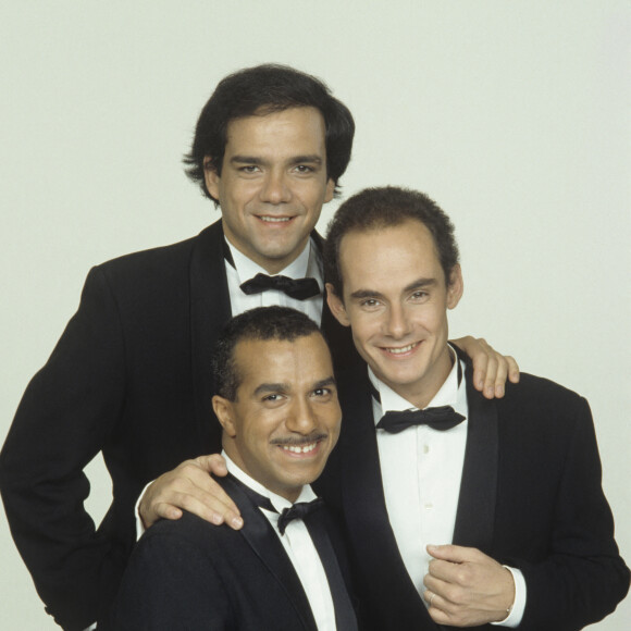 Archives - En France, à Paris, portrait studio sur fond rouge des Inconnus, de gauche à droite, Pascal Légitimus au premier-plan, Didier Bourdon et Bernard Campan en décembre 1991.
