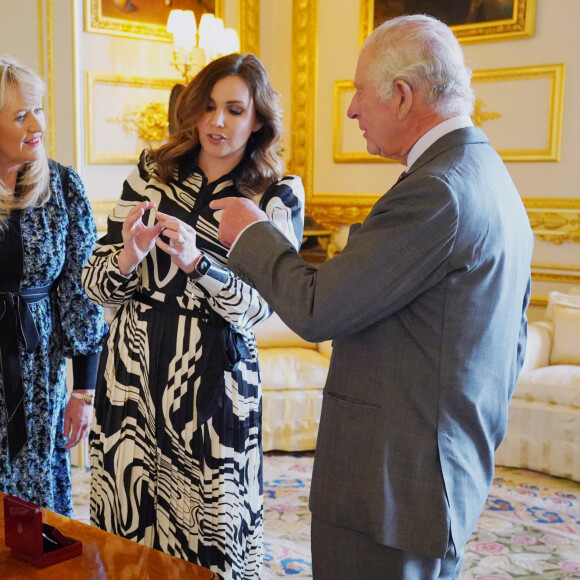 Le roi Charles III d'Angleterre, se voit présenter les pièces à son effigie, frappées à l'occasion de son prochain couronnement, au château de Windsor, le 13 avril 2023. La PDG de Royal Mint, Anne Jessopp et la directrice, Rebecca Morgan, montrent au souverain les pièces de 50 pence et de 5 livres qui seront mises en circulation ce mois-ci, avant l'événement du 6 mai 2023. 